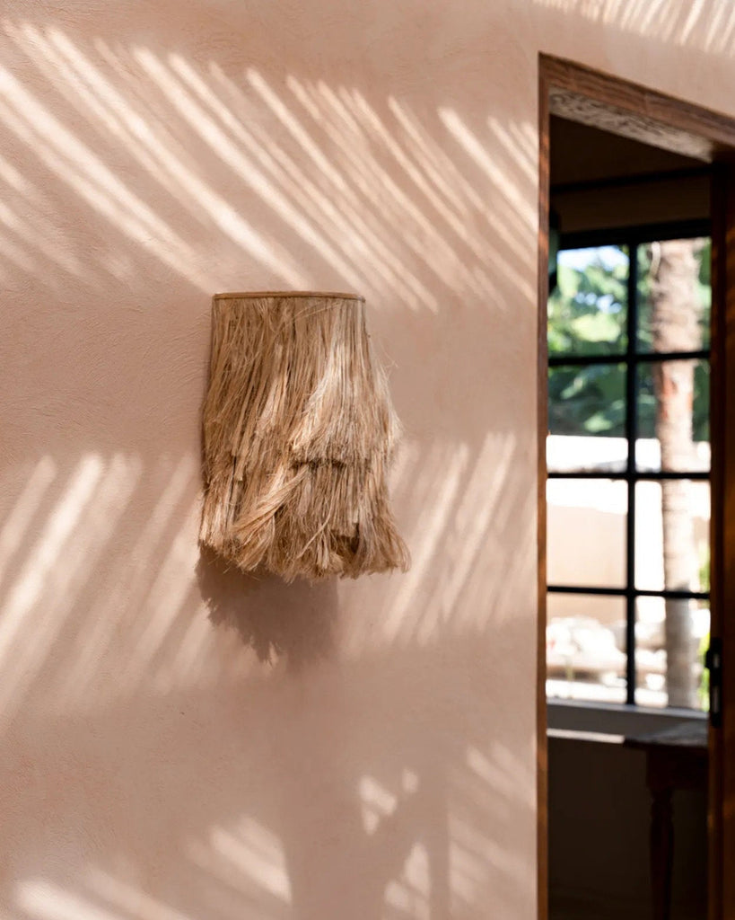 Decorative wall piece on a light pink wall with natural light casting shadows.