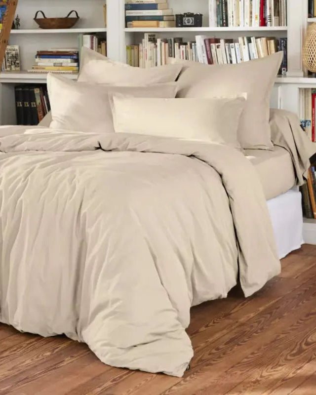 Beige bedding set on a bed with bookshelves in the background