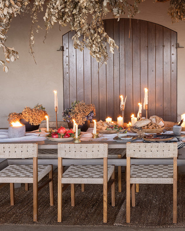 Dining table set for a meal with candles and decorative elements in a rustic setting.