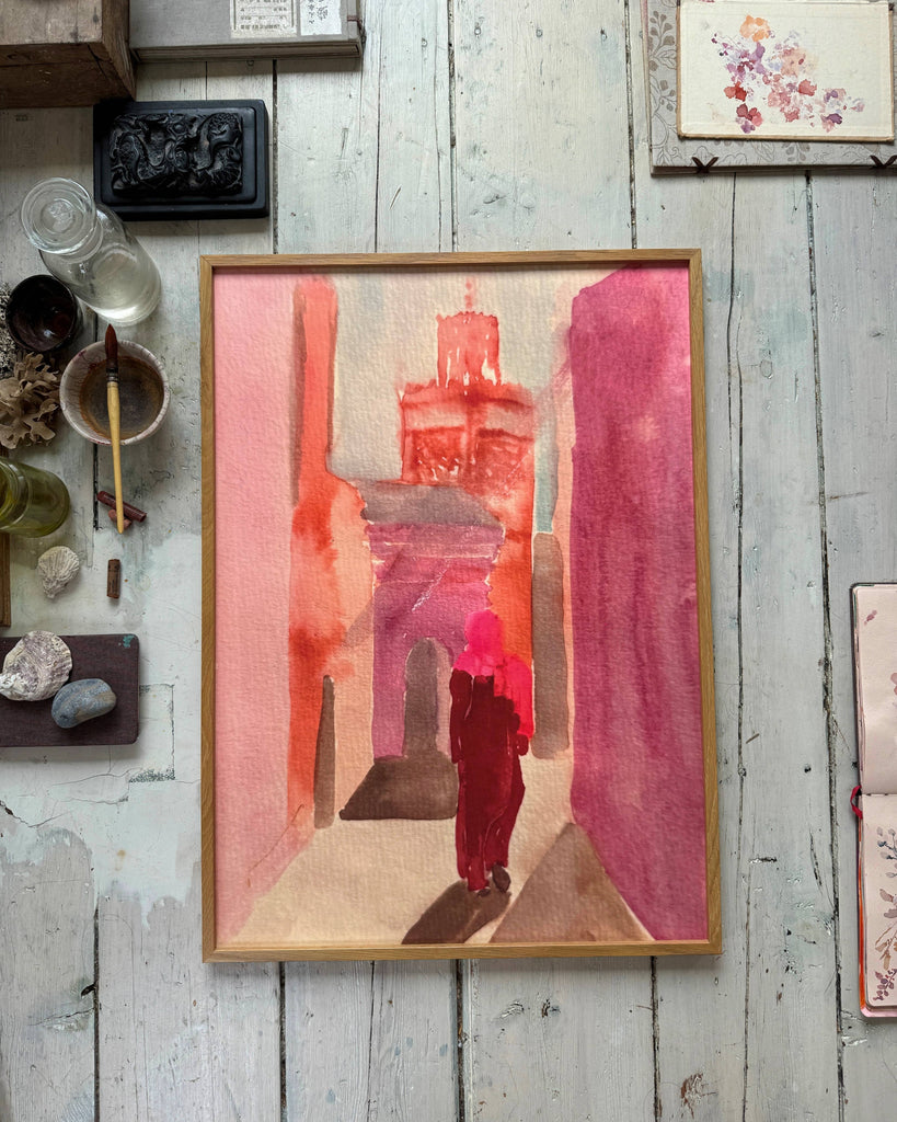 Framed artwork with a red and pink abstract design on a rustic wooden surface.
