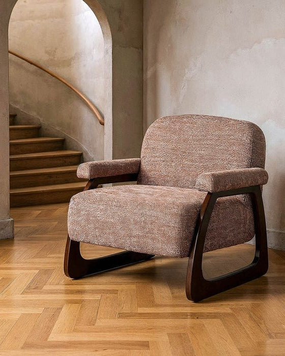 Brown armchair with wooden legs on a wooden floor in a room with stairs.
