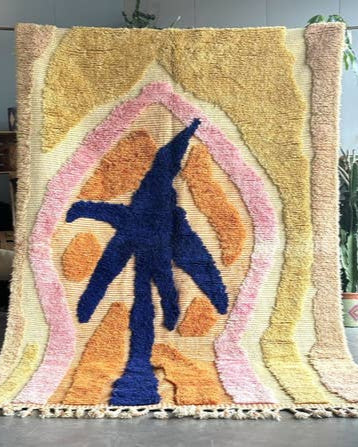 Colorful abstract rug with a blue figure in a geometric design on a gray floor.