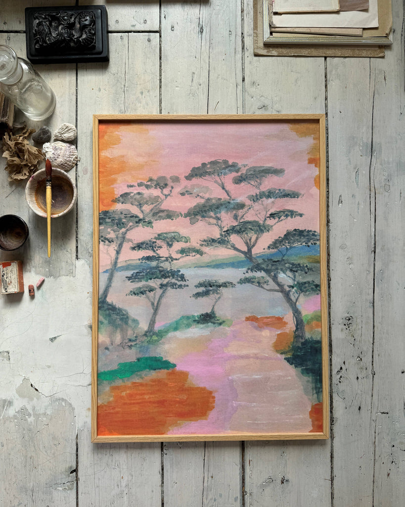 Framed artwork of a landscape with trees on a rustic wooden surface.