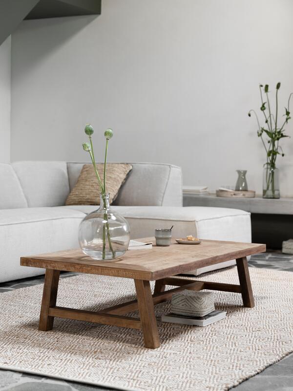 Modern living room with a wooden coffee table, white sofa, and decorative items.