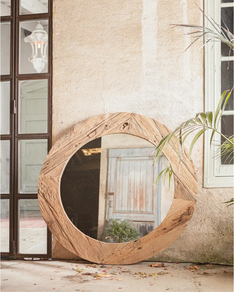 Round wooden mirror on a wall with a neutral background