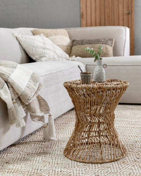 Wicker side table with decorative items in a living room setting