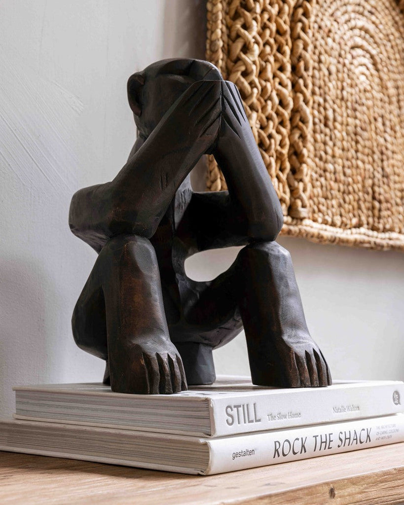 Black bear sculpture on top of books with a textured wall in the background