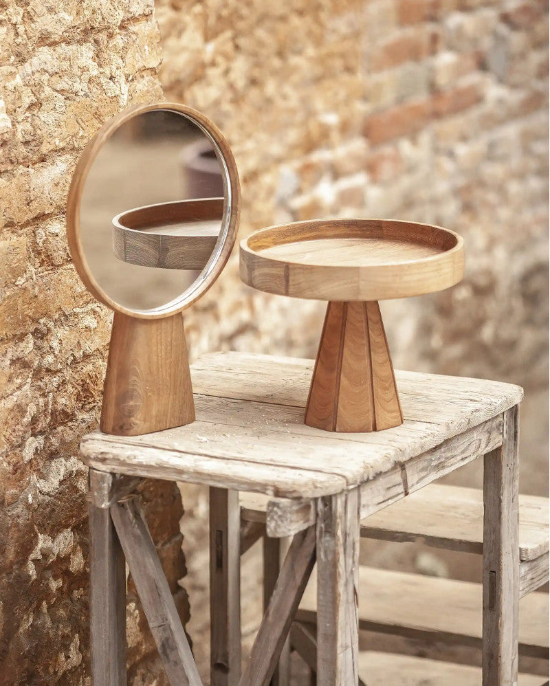 Wooden mirror and tray set on a rustic table against a stone wall.