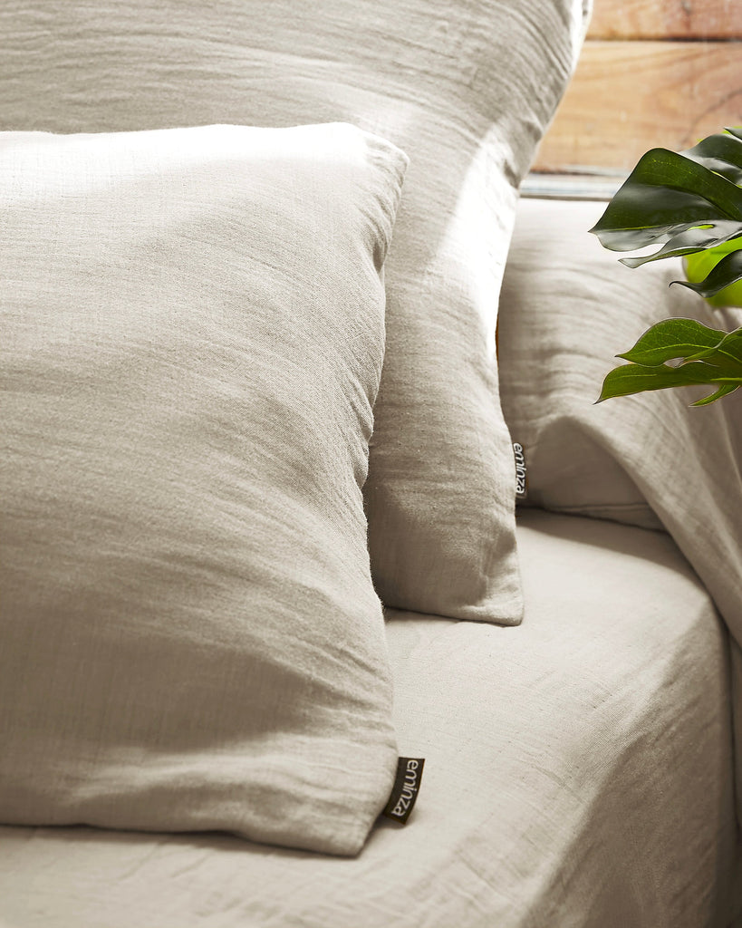 Beige bedding set with pillows and a plant on a wooden surface